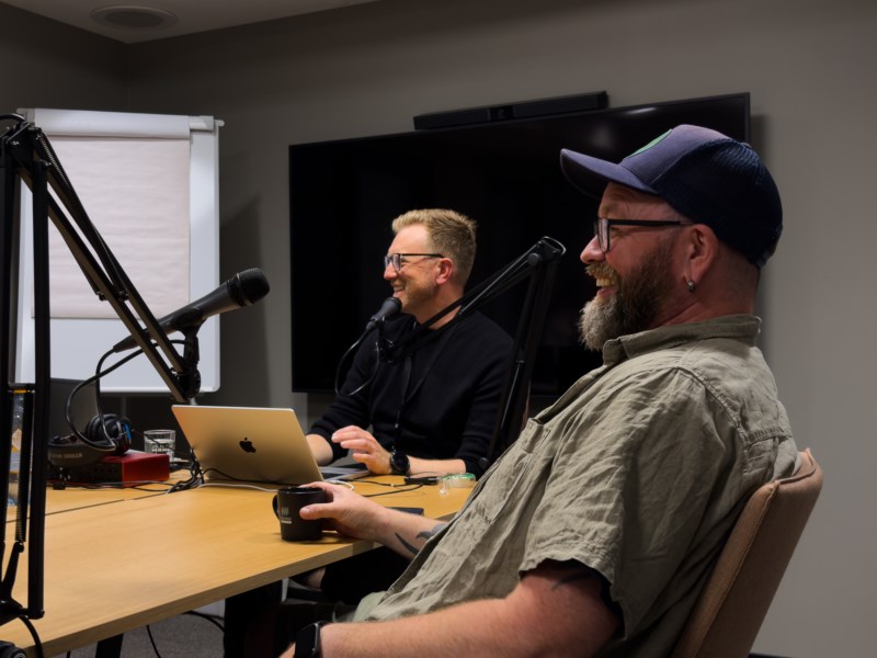 Verten og en gjest ler sammen under innspilling av første episode av podcasten Med hjerte for Melhus – god stemning rundt bordet på møterom i MelhusBanken.