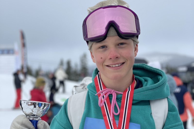 Ung mann med alpinbriller holder en pokal og smiler.