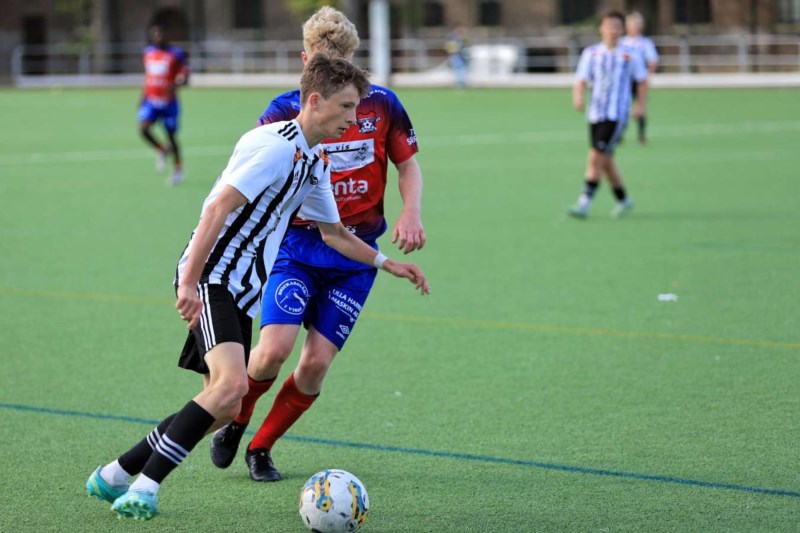 En fotballspiller dribler seg unna en motstander.