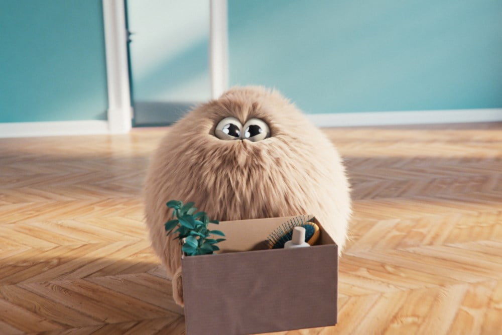 En søt hårdott i ei tom stue bærer på ei pappeske med en plante og en hårbørste i.