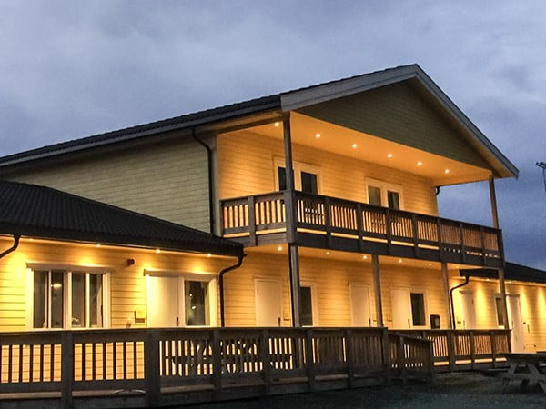 Et hus i skumring med hyggelige lys på verandaen rundt huset.