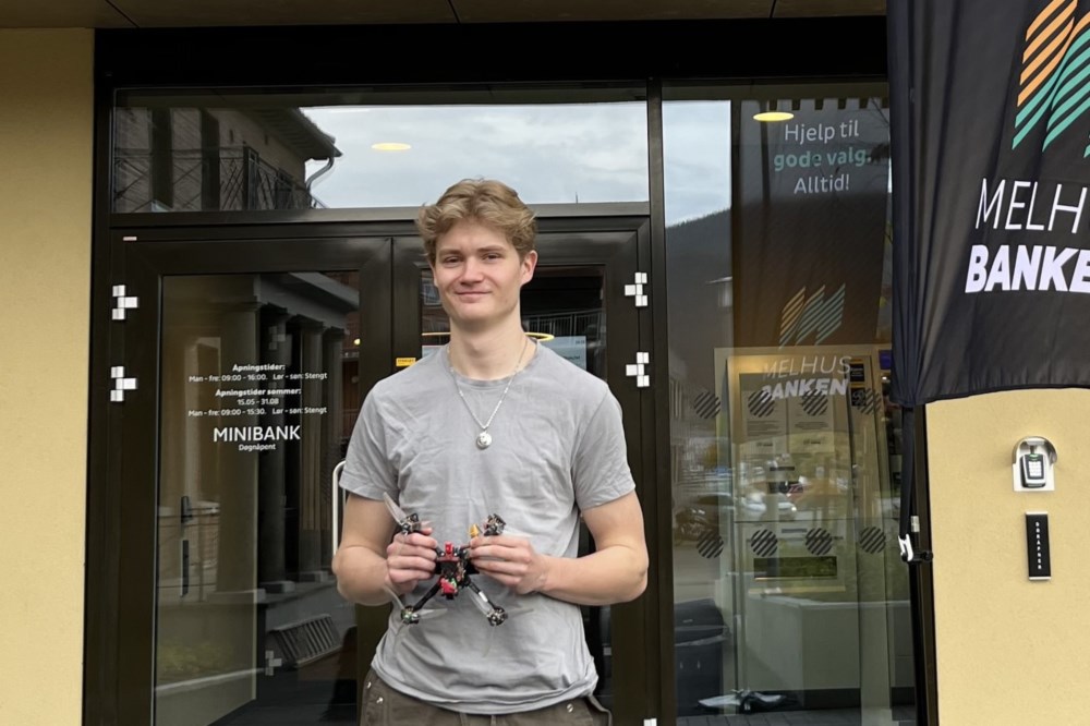 Ung mann holder en drone og smiler.