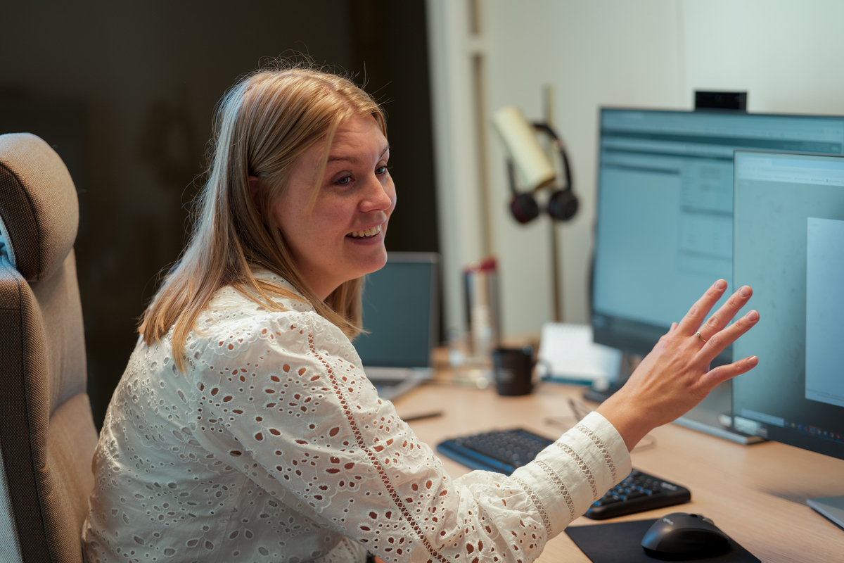 Kvinne smiler foren en pc-skjerm.