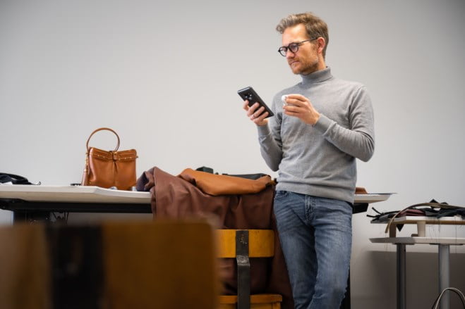 Skredder som tar en kafe og ser på mobil