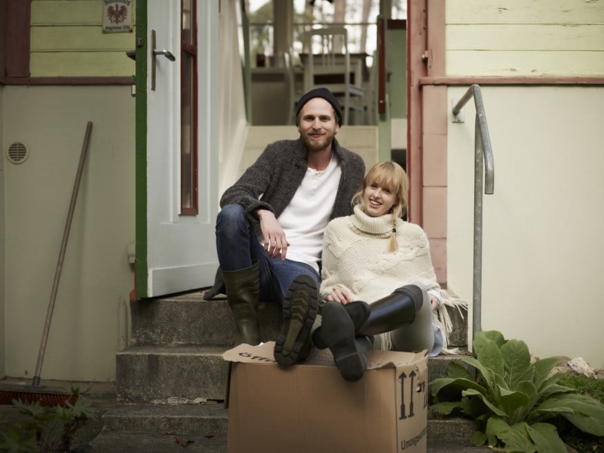 Par som sitter på trappa utenfor huset sitt